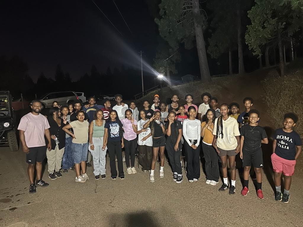 Youth group and leaders gathered outdoors at night during a camp retreat
