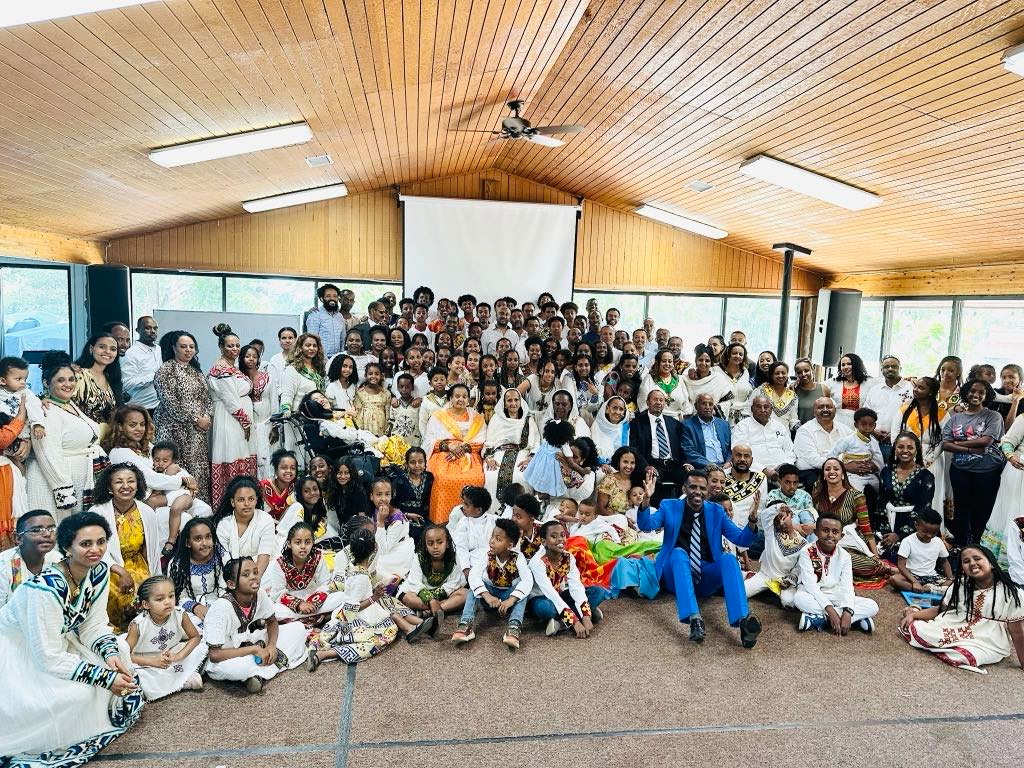 Large congregation in traditional Eritrean white attire posing for a fellowship group photo