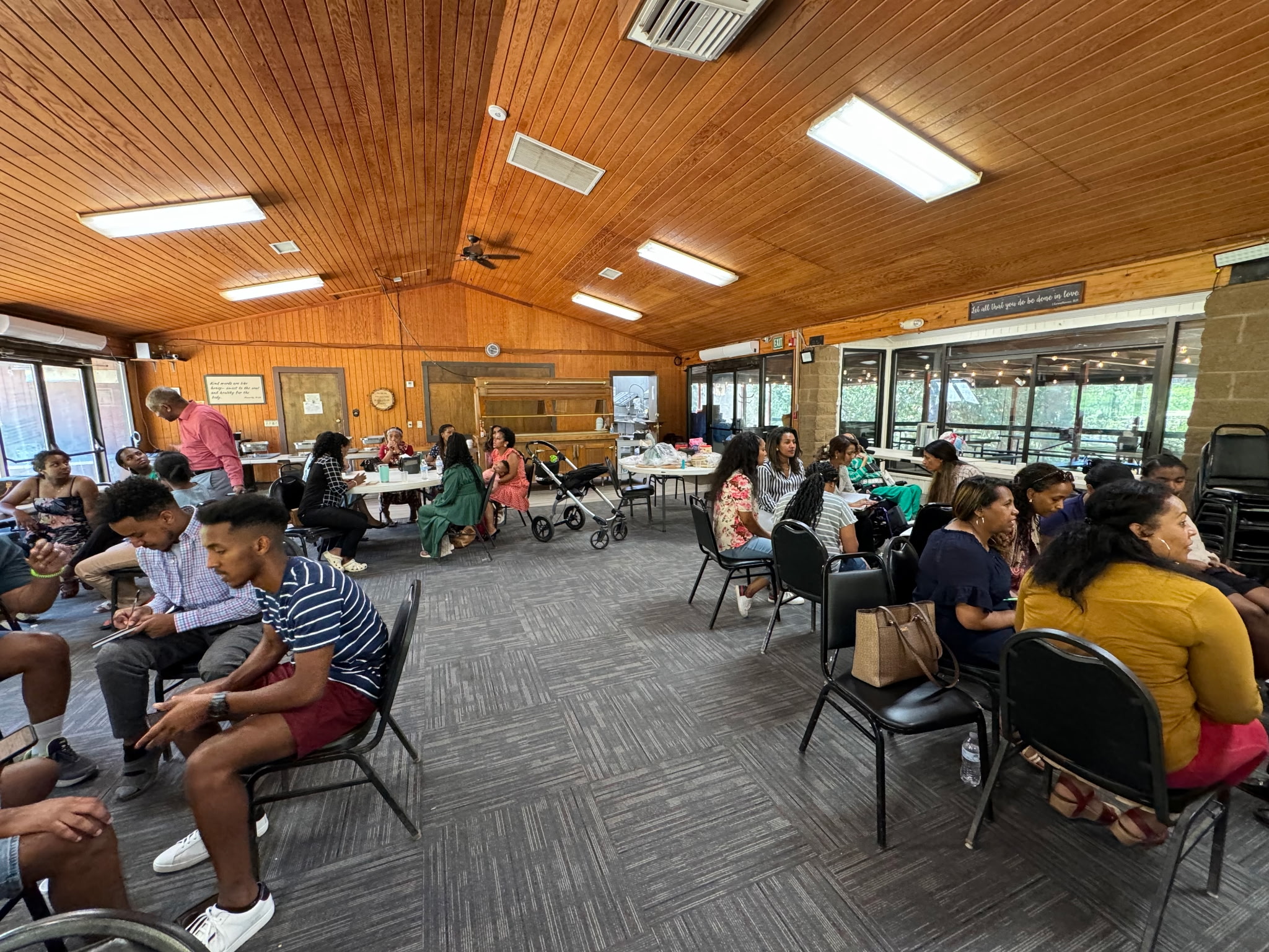 Members gathered in small discussion groups inside a wood-paneled fellowship hall