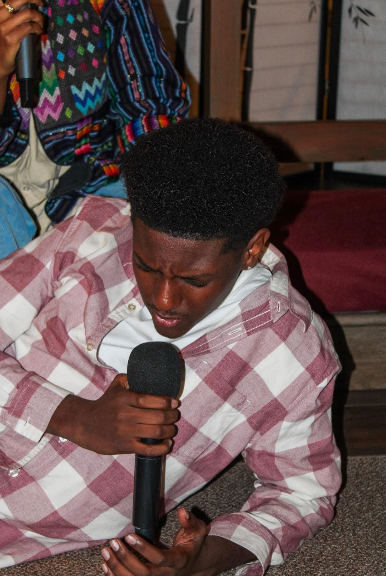 Young man singing into a microphone with eyes closed during a youth worship gathering
